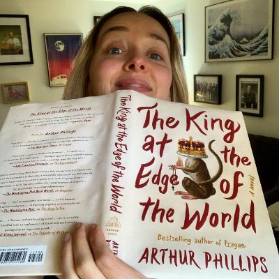 Jess Weixler posing for a photo shoot while holding a book. 